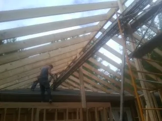 Rafters going up over a new addition with a worker on the wall in Lostine