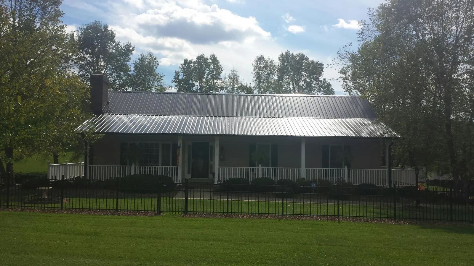 Gray metal roof on a brick ranch with a full width front porch — Gutter Guard Installation work by our crew in Lostine