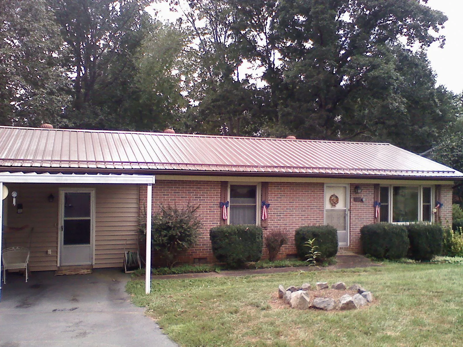 Bronze metal roof and carport on a brick ranch home — Roof Repair work by our crew in Lostine