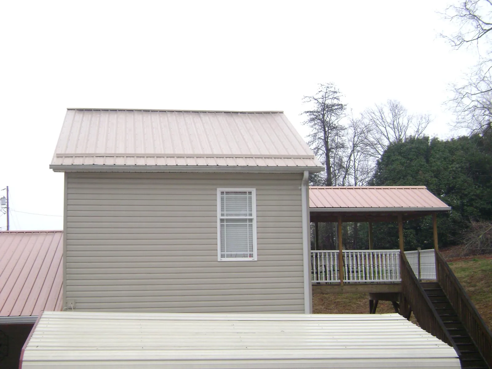 Tan metal roofs on a two story addition and attached porch, from a Roof Replacement job in Lostine