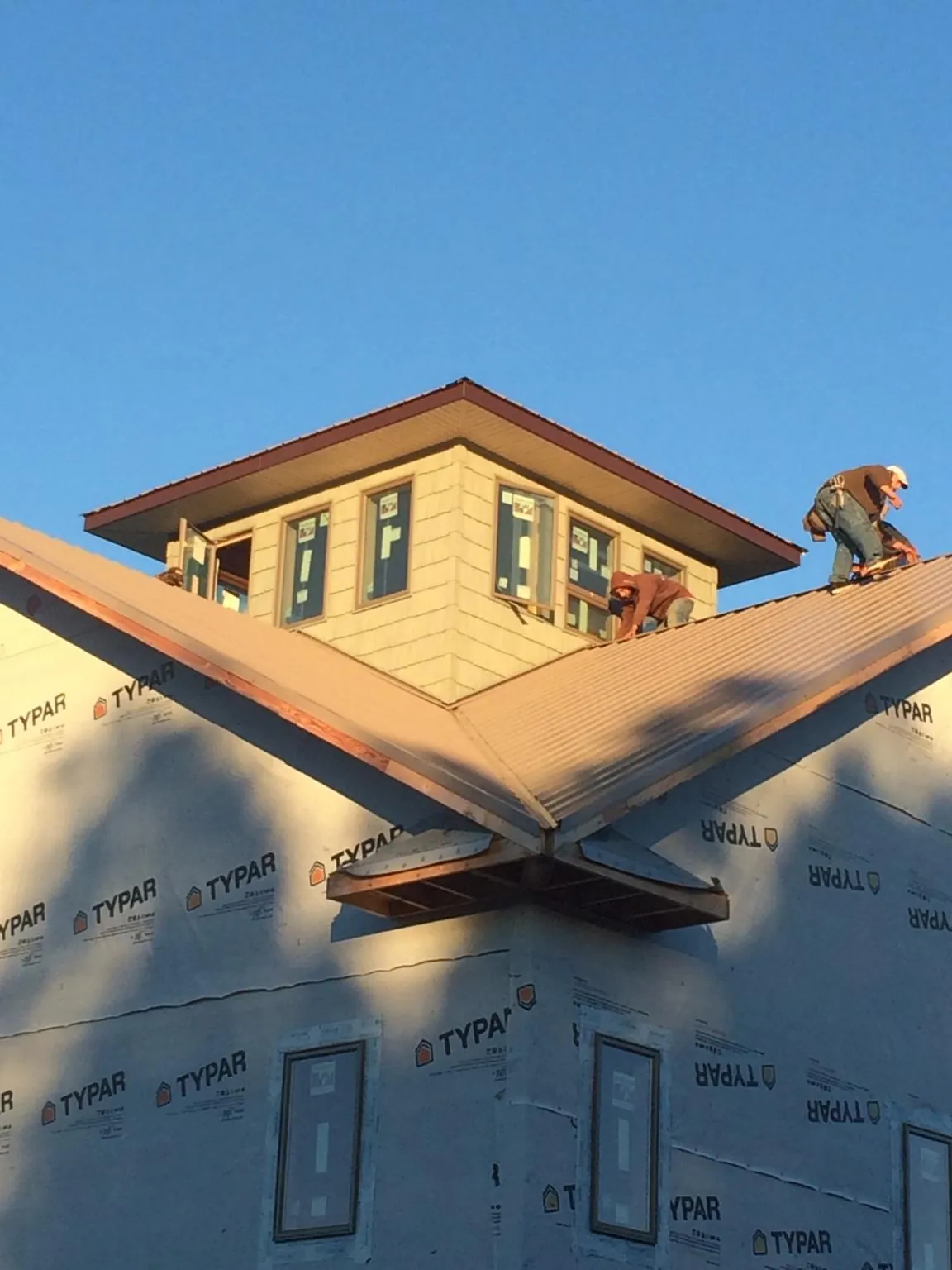 Roofers working around a rooftop cupola on a new metal roof at sunset — Roof Waterproofing in Lostine by Roofing Brothers